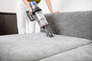 Cleaning sofa with a modern cordless vacuum cleaner